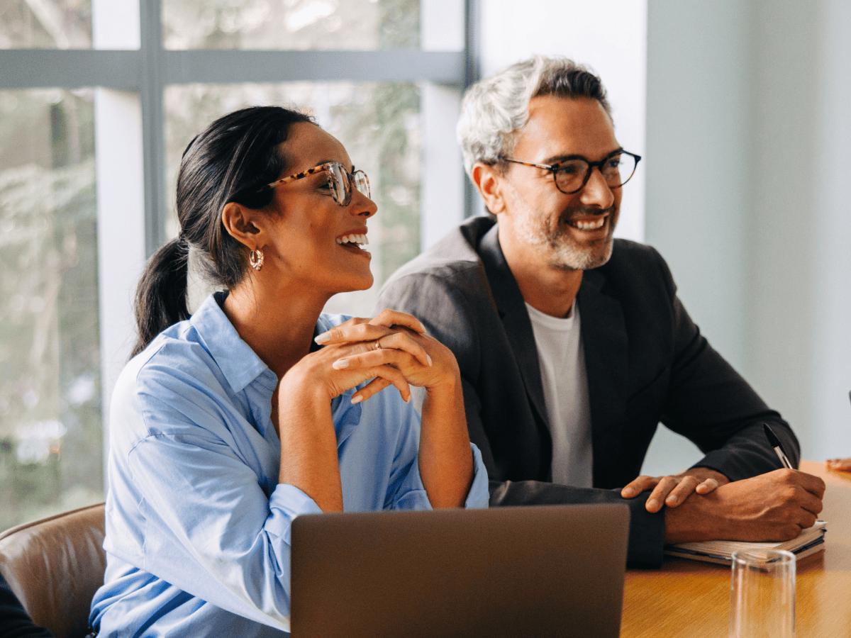 Two colleagues smiling over a laptop