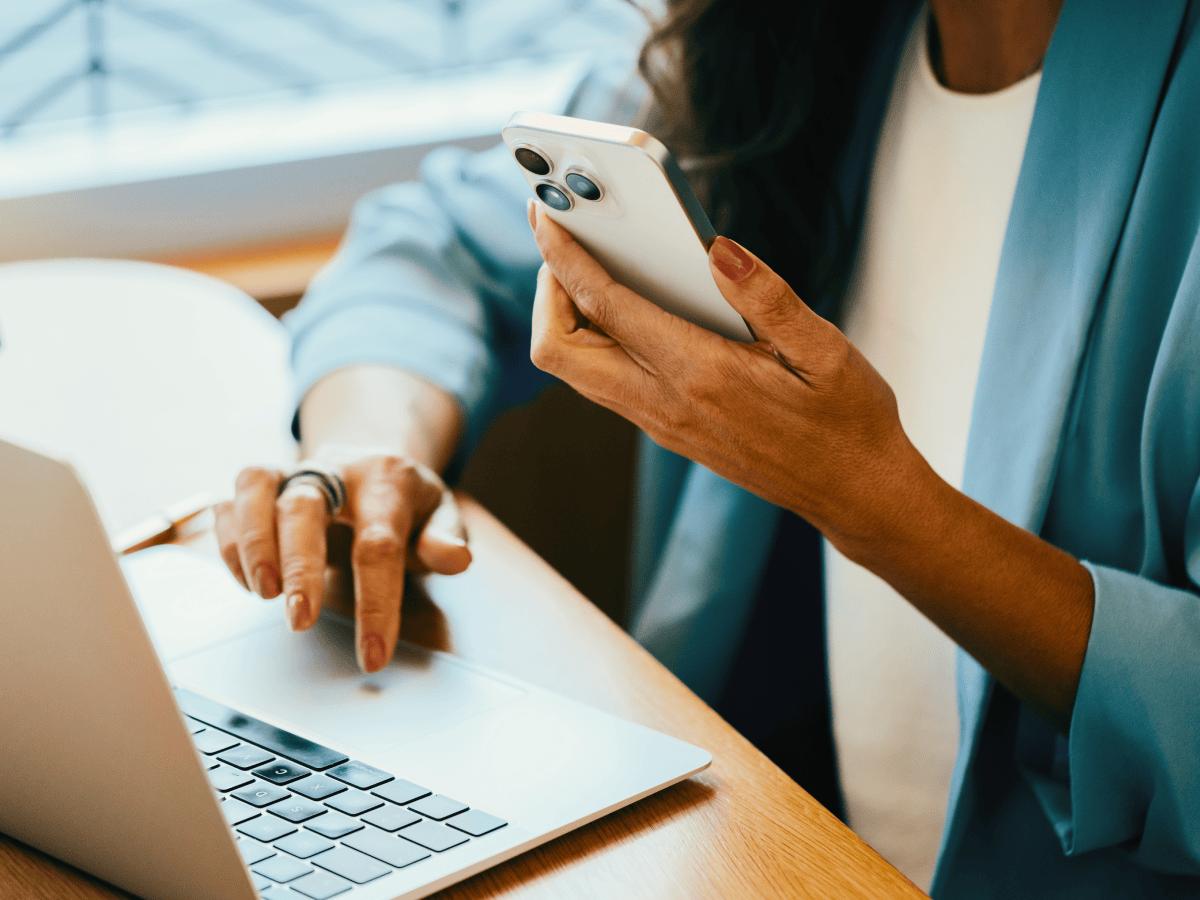 Person using a phone and laptop at a desk