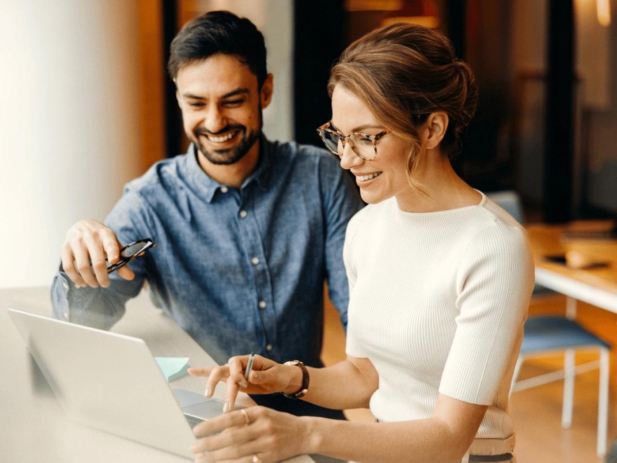 Two colleagues reviewing work on a laptop