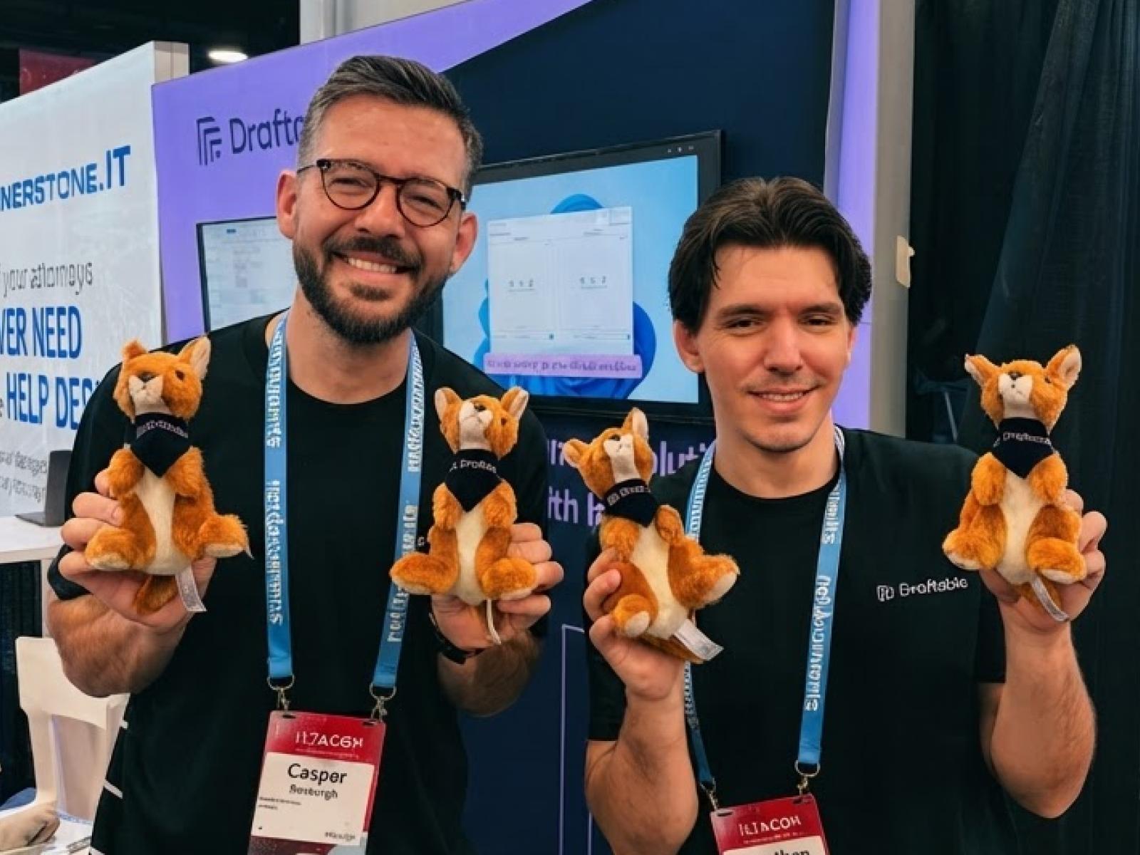 Two Draftable team members at a conference holding plush toys