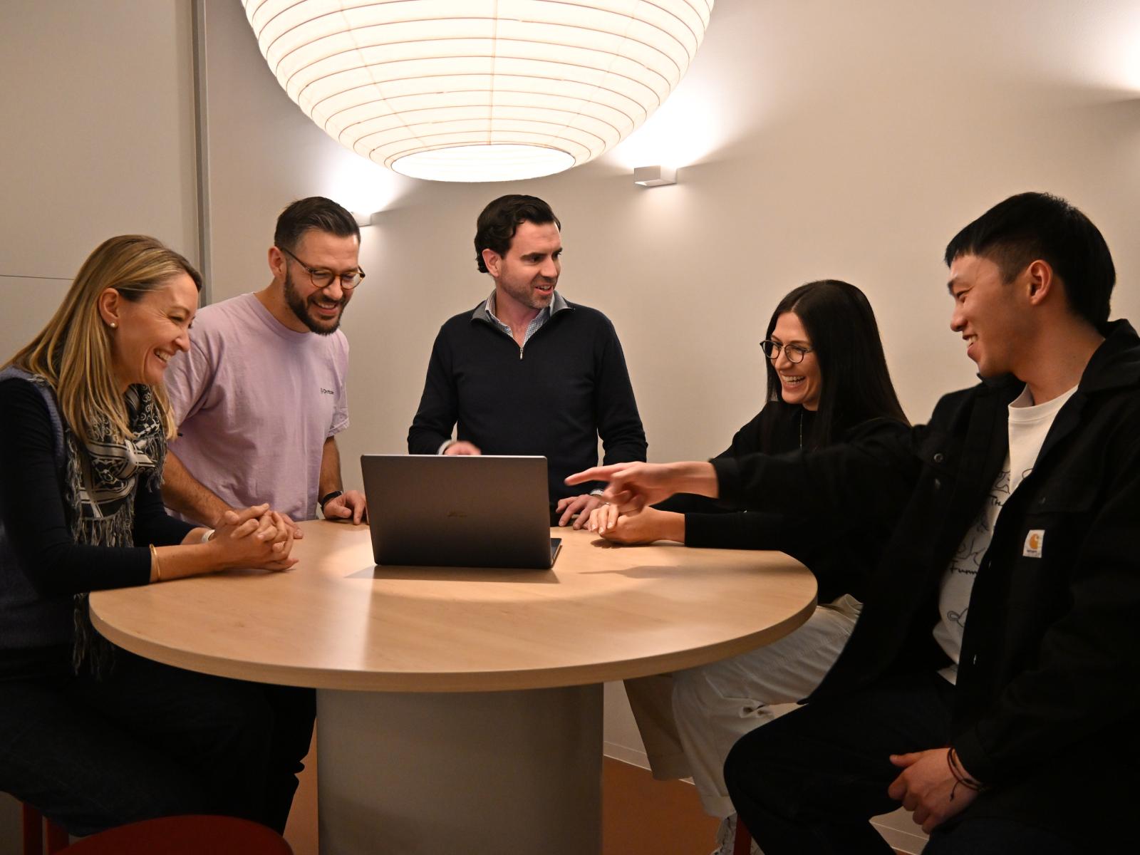 Draftable team meeting around a table with a laptop