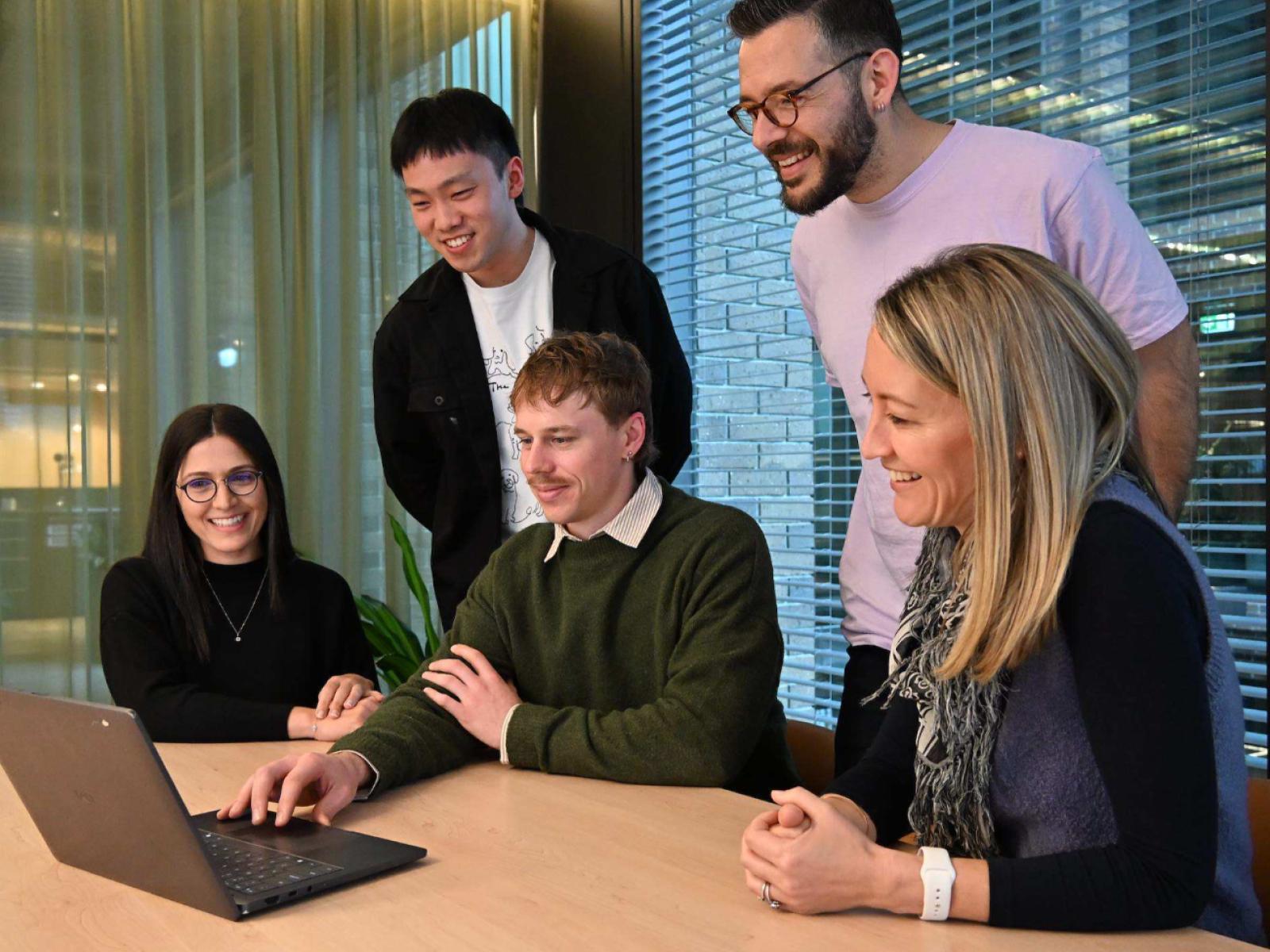 Draftable team collaborating around a laptop