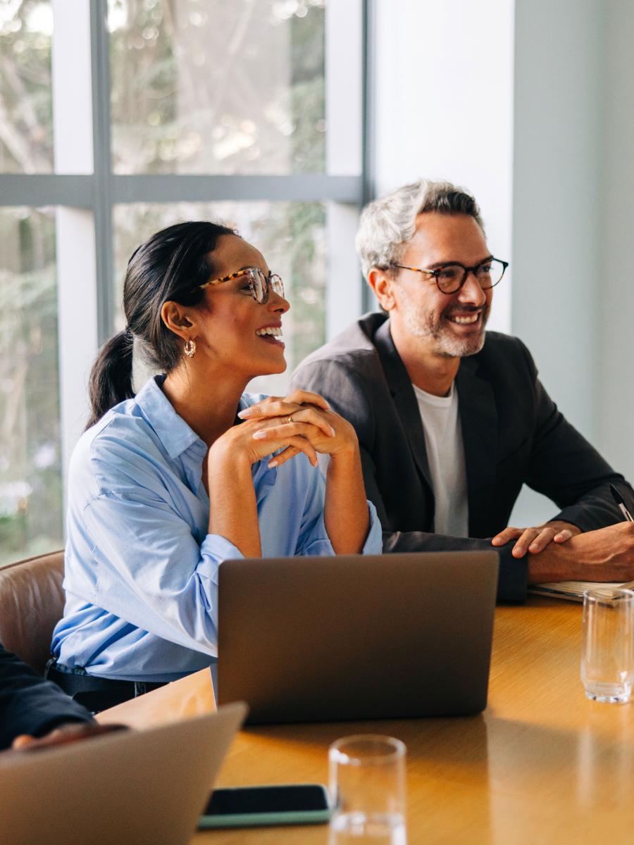 Two colleagues smiling over a laptop