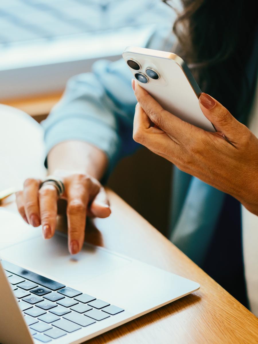 Person using a phone and laptop at a desk