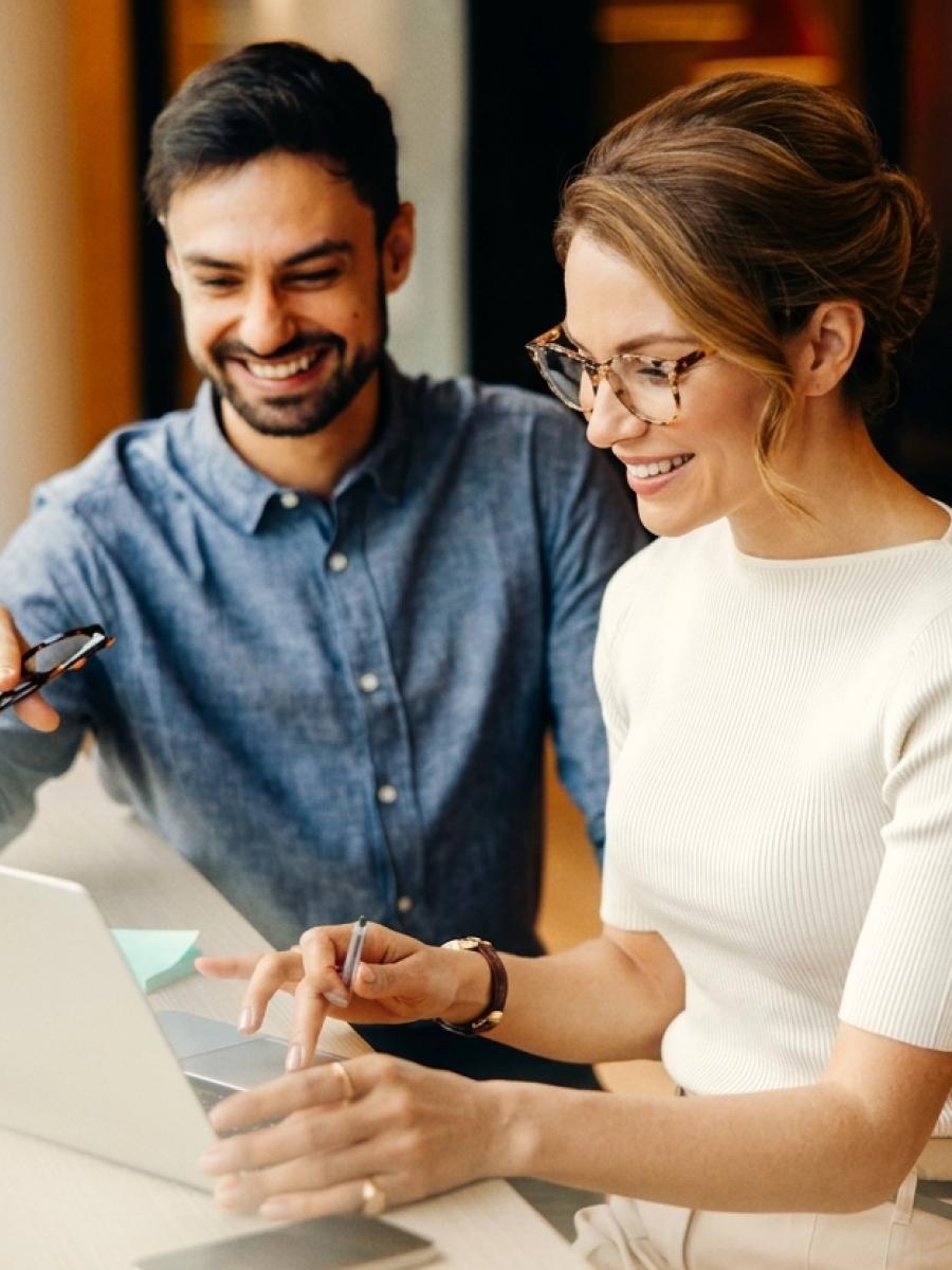 Two colleagues reviewing work on a laptop