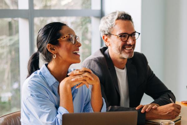 Two colleagues smiling over a laptop