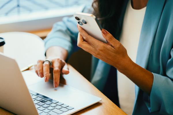 Person using a phone and laptop at a desk